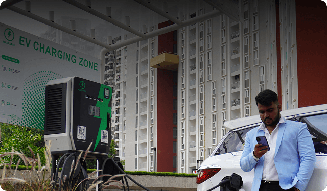 A man charging his electric car at an apartment building parking area