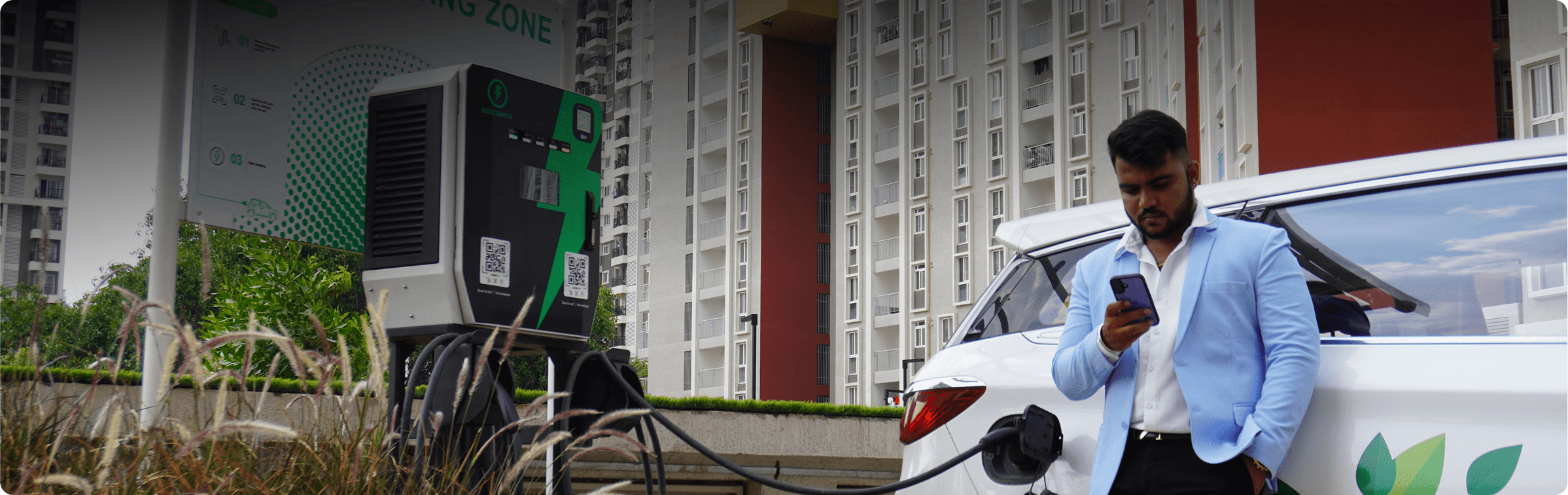 A man charging his electric car at an apartment building parking area